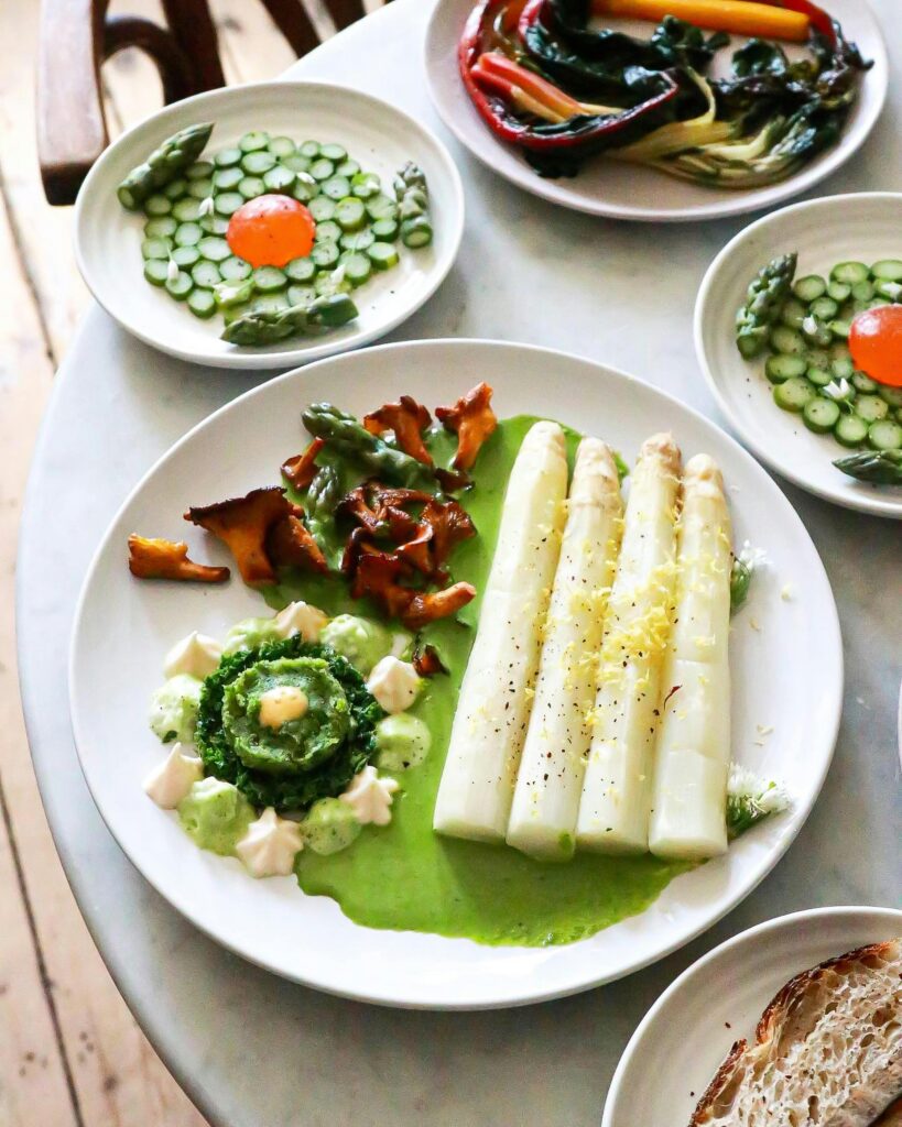 Delicious vegetarian dish with asparagus and assorted vegetables on white plates.